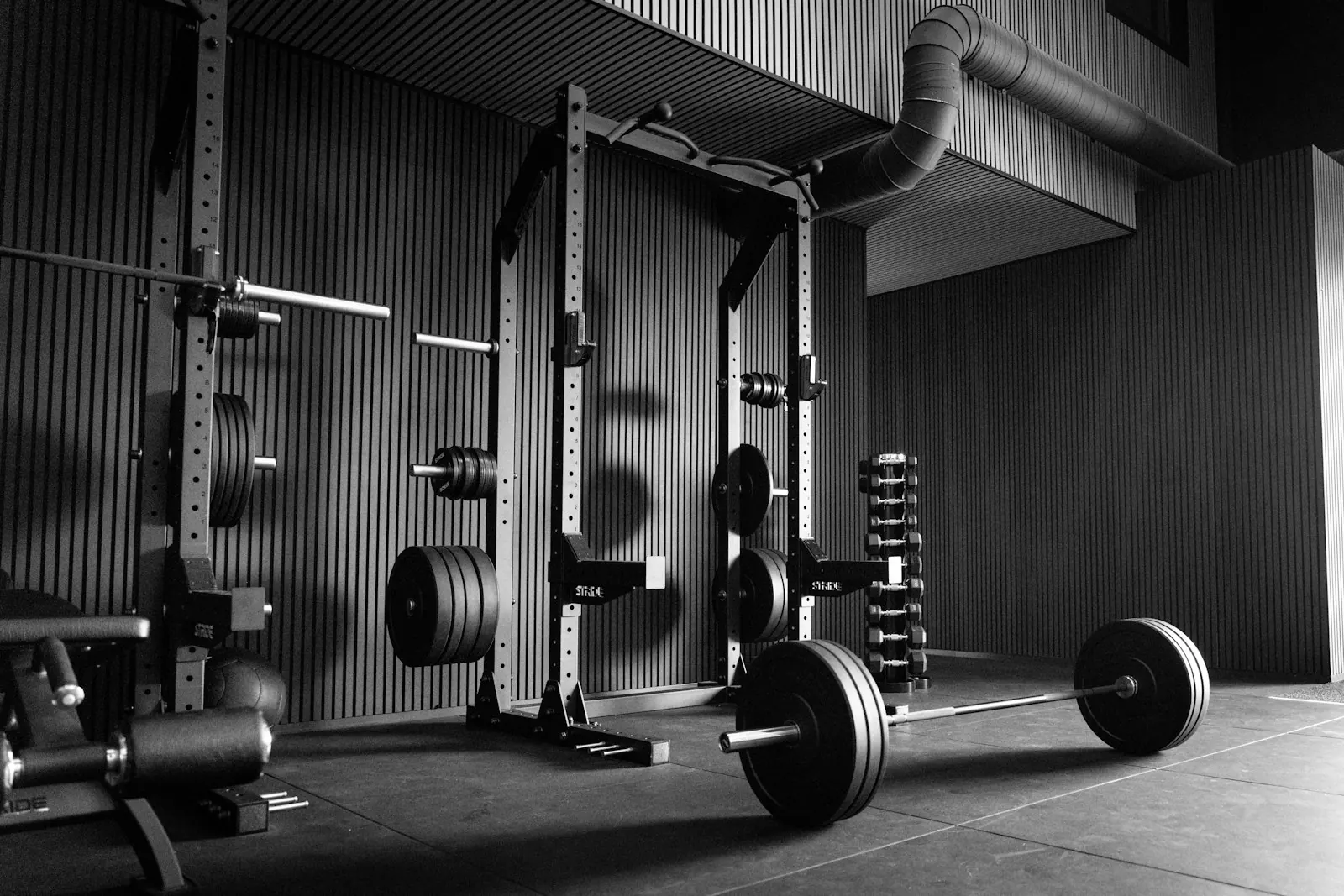 Power rack and barbells in a quiet gym, black and white